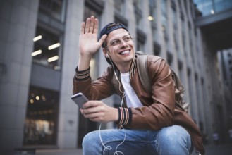 Man Sitting Listening Music Earphones Concept. Cheerful young guy listening the music