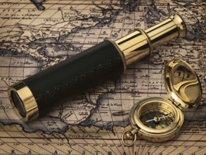 Travelling theme: vintage telescope and compass at antique map