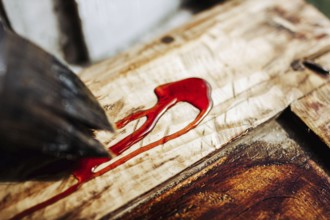Close-up of a red stain and brush on wooden surface showcasing texture and finish