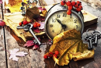 Od clock book and the keys on the wet table strewn with autumn leaves.Photo tinted