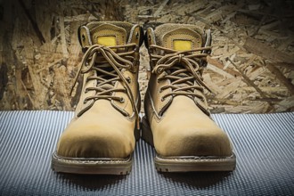 Two brown working boots on plywood background