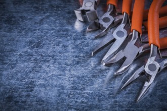 Insulated electric metal nippers gripping tongs on scratched metallic surface