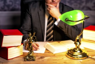 Office of a lawyer with books and a statue of Lady Justice, goddess Justitia, on the desk