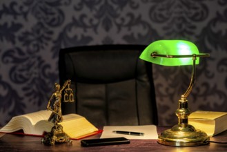 Office of a lawyer with books and a statue of Lady Justice, goddess Justitia, on the desk