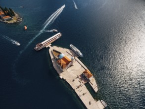 Boats moored near the island of Gospa od Skrpjela on the background of St. George island. Top view.