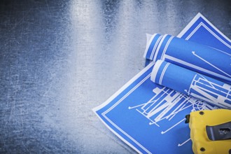 Composition of blue construction plans measuring tape on metallic background