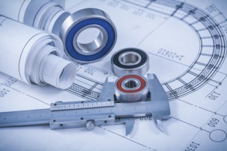 Rolls of construction plans rolling bearings and slide caliper on blueprint industrial concept