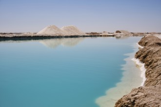 Salt lake with turquoise water and white salt hills on the shore. Siwa oasis, Western Desert, Egypt