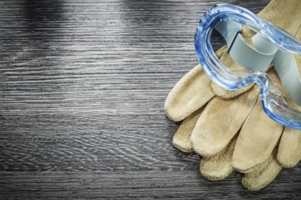Protective gloves plastic goggles on wooden board