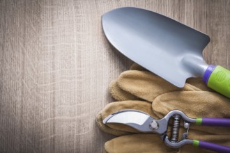 Pruning shears hand spade and leather safety gloves on wood board gardening concept