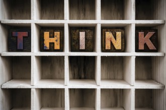 The word THINK written in vintage ink stained wooden letterpress type in a partitioned printer's