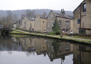 Houses alongside the rochdale canal in hebden bridge with reflections in the water and lock gates