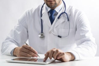 Close up of male doctor hands using tablet computer. Physician in white medical uniform with