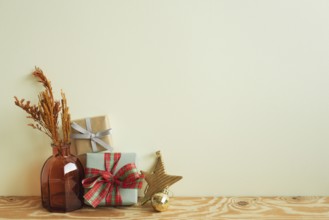 Gift boxes, vase of dry flower, christmas ornament on wooden table. ivory wall background. winter