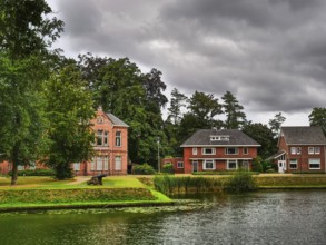 Houses on the lakeshore, surrounded by trees and plants, with a cloudy sky, groenlo, gelderland,