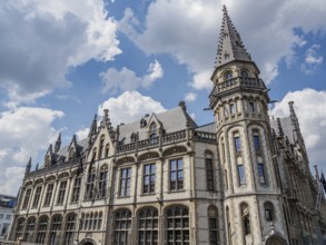 Large historic building with Gothic architecture and towers under a blue sky with clouds, Ghent,