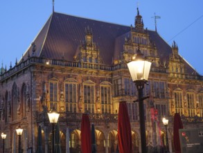 Night shot of a historic building with Gothic architecture, illuminated by lanterns and a cosy