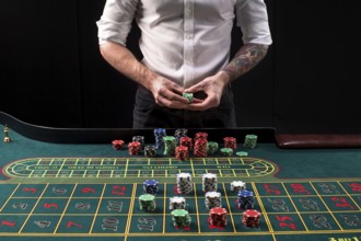 A close-up vibrant image of green casino table with roulette, with the hands of croupier and