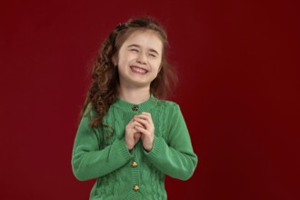 Portrait of a laughing tiny kid with a long, curly hair looking happy. Charming girl in a knitted