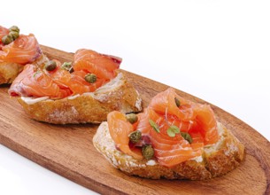 Food, Delicious canapés topped with smoked salmon and capers rest on a wooden platter. The vibrant