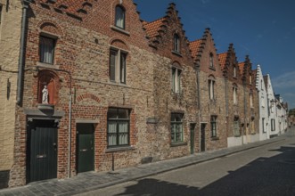 Brick facade of old houses with a blue sunny sky in an empty street of Bruges. With many canals and