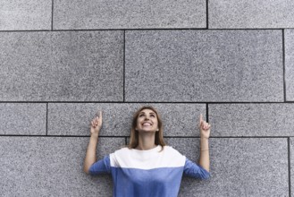 Cheerful girl at the street, show a big sale, or nice offer. Advertise concept. People, travel and