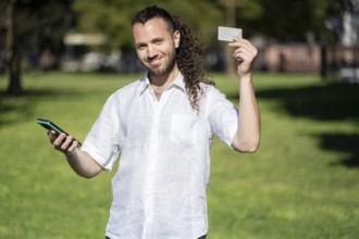 Young man making an online purchase with his credit card and his phone