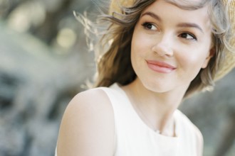 Smiling woman in a straw hat with her hair blowing in the wind. Portrait.