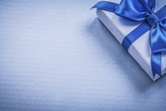 Present box with bow on blue background copyspace holidays concept