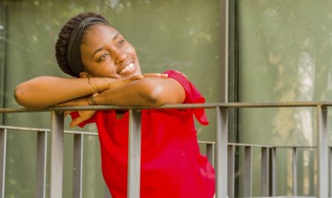 Woman leaning on a balcony railing, smiling brightly in natural light, Taken in Daejeon, South