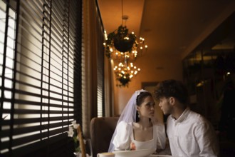 Bride and groom share an intimate look in a romantic cafe setting