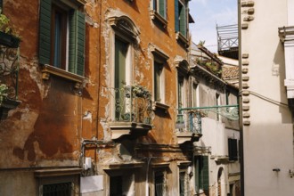 Close-ups of building facades in Venice, Italy. Green wooden door at bottom of brick house. Balcony