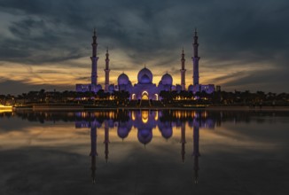 A picture of the Sheikh Zayed Grand Mosque reflected on the Oasis of Dignity pool, at sunset