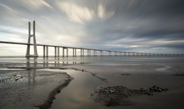 Vasco da Gama Bridge at sunset with dramatic cloudy sky in Lisbon Portugal. Long exposure