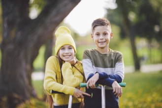 Caucasian children twins boy and girl schoolchildren age pose together in sunny weather in autumn