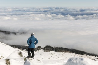 Freestyle skier is looking from the top of a peak of Vitosha mountain covored in clouds. He is