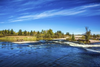 Thin flying cirrus clouds and broad Winnipeg River. Landscape in the Old Pinawa Dam Park. Trend of