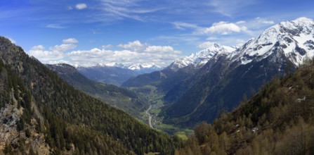 Beautiful top view panorama of high snow-covered mountains and valley with road and village in