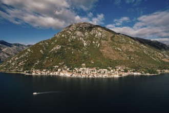 Boat sails along the Bay of Kotor against the backdrop of the coast of Perast at the foot of the