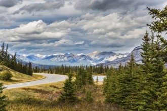 The road to distant snow-capped mountains in the Rockies of Canada. Rocks and lakes under flying