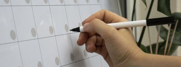 Female hand writing with marker on Monthly PLANNER. Magnetic board with the days of the month.