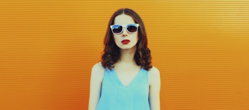 Portrait of young woman posing wearing dress on an orange background