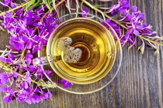 Herbal tea in a glass cup, fresh flowers fireweed against the backdrop of wooden planks on top