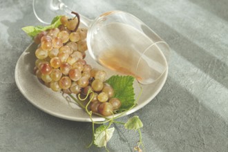 A branch of white grapes, on a gray plate, with a glass of white wine, top view, natural light,