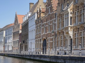Historic buildings on the banks of a canal with striking Gothic facades and a clear blue sky,