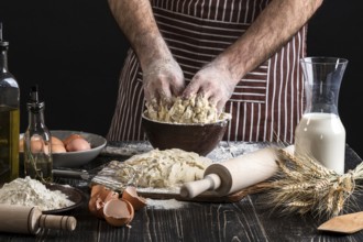 A handful of flour with egg on a rustic kitchen. Against the background of men's hands knead the
