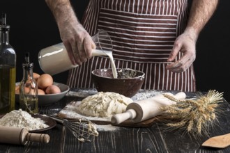 Baker in uniform pouring milk from plastic bottle into bowl. A handful of flour with egg on a