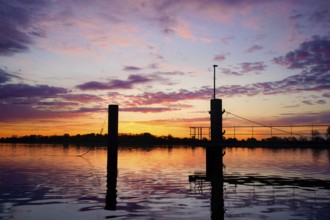 Bollard on the water in a pink morning sky with atmospheric reflection at dusk, An der Kaje /