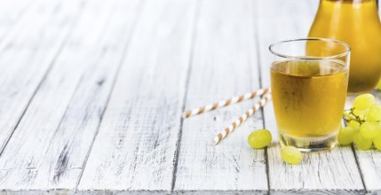 Healthy Grape Juice on a wooden table as detailed close-up shot (selective focus)