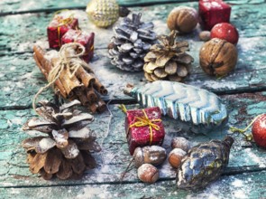 Gifts and decorations for Christmas on wooden background strewn with pine cones and spices